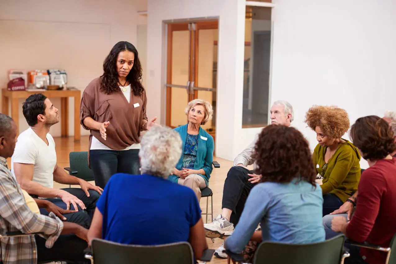 A woman leads a group discussion in a casual meeting room.