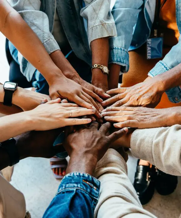 Diverse group stacking hands in unity and teamwork.