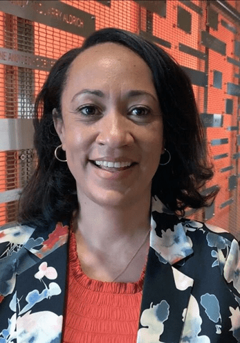 Smiling woman wearing a floral blazer and red top.